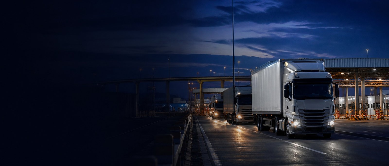 Cross-border freight trucks moving through a China-origin land gateway at blue hour