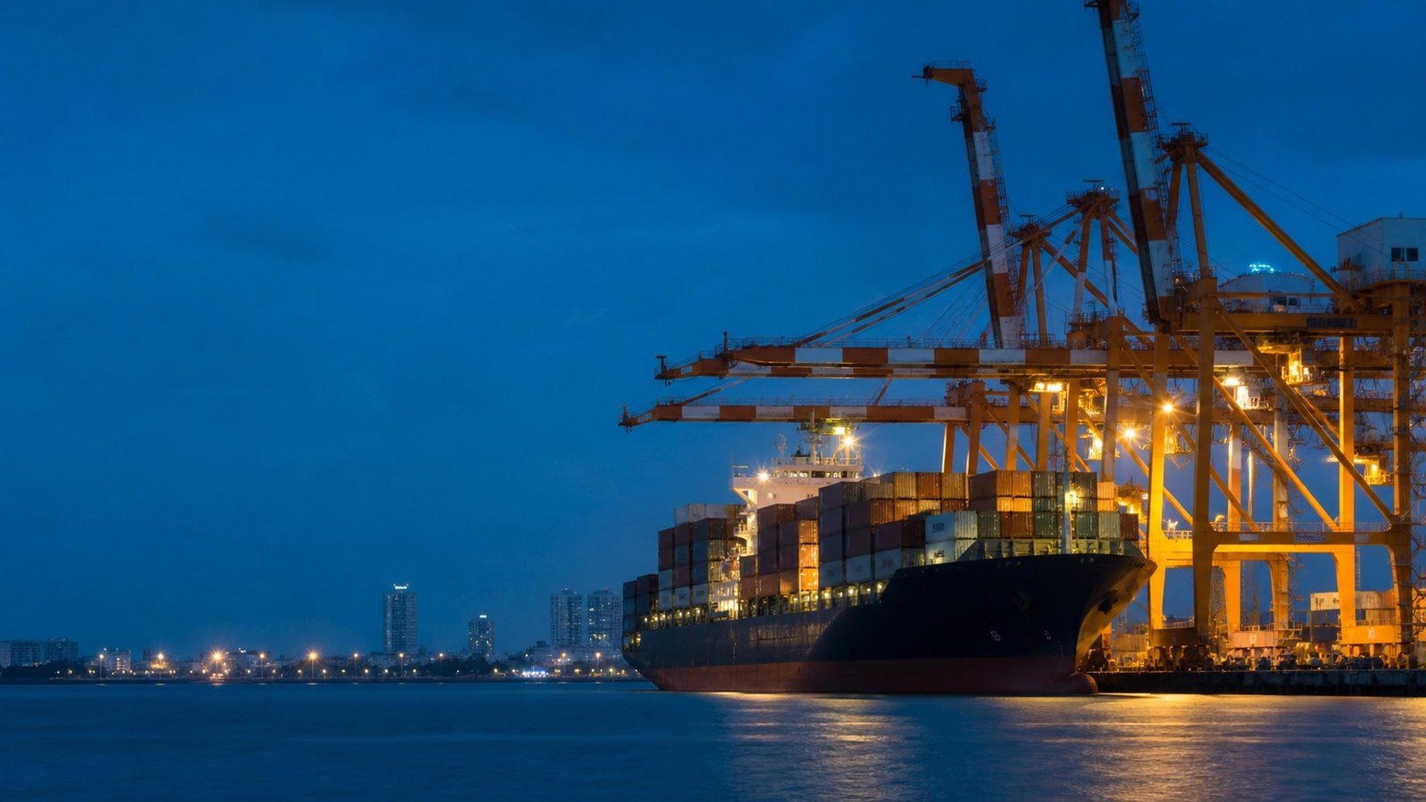 Container vessel and quay cranes at the Port of Colombo during blue hour