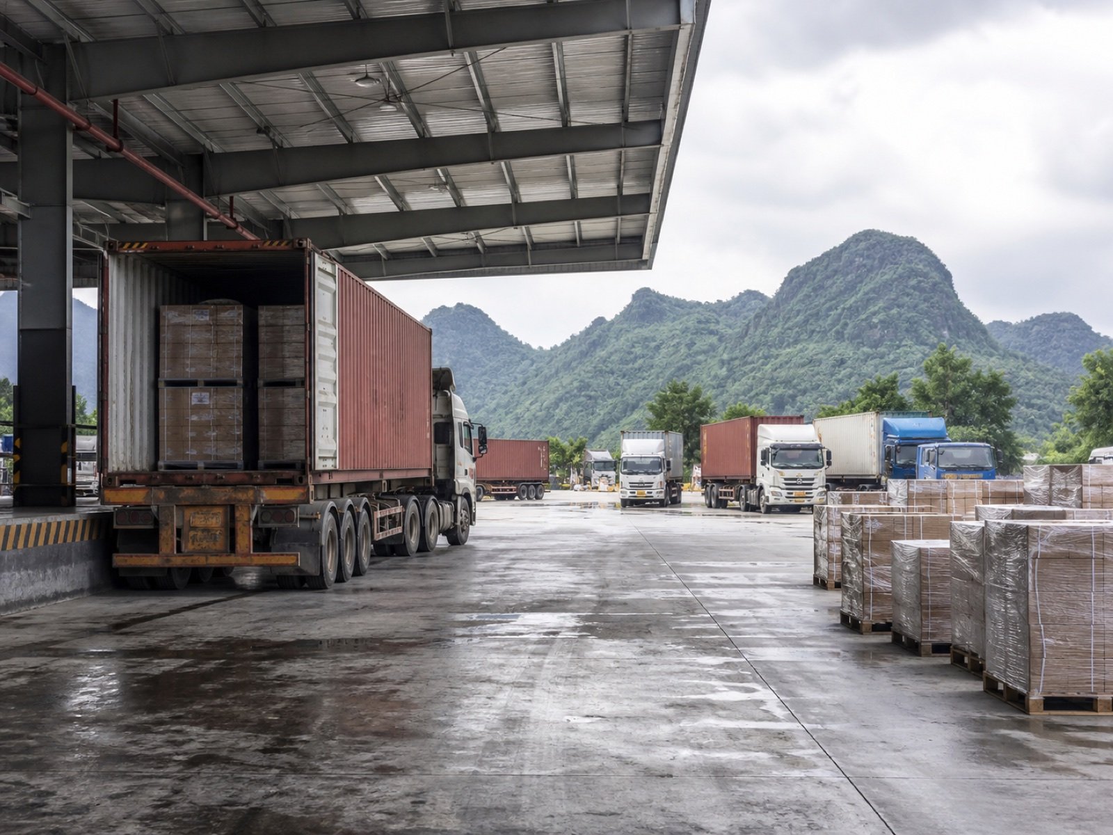 Container trucks and palletized cargo at a covered cross-border transfer yard
